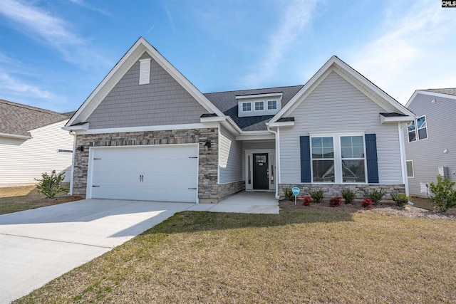 craftsman-style house featuring stone siding, driveway, an attached garage, and a front lawn