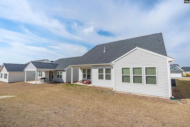 back of house featuring a patio area, a lawn, and roof with shingles