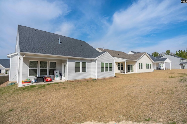 back of property with a lawn, roof with shingles, and a patio area