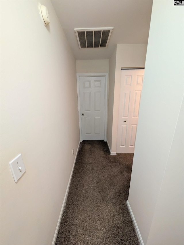 corridor with dark colored carpet, visible vents, and baseboards