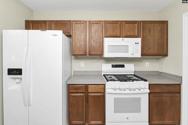 kitchen featuring brown cabinets, white appliances, and light countertops