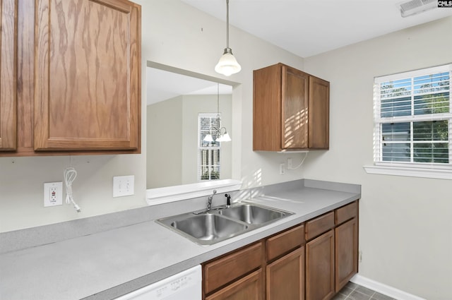 kitchen featuring visible vents, decorative light fixtures, light countertops, brown cabinets, and a sink