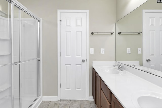 full bathroom featuring a sink, double vanity, a shower stall, and tile patterned flooring