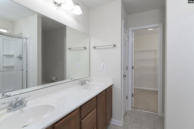 bathroom featuring a shower stall, double vanity, tile patterned floors, and a sink