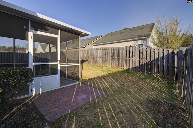 view of yard with a patio area, a fenced backyard, and a sunroom