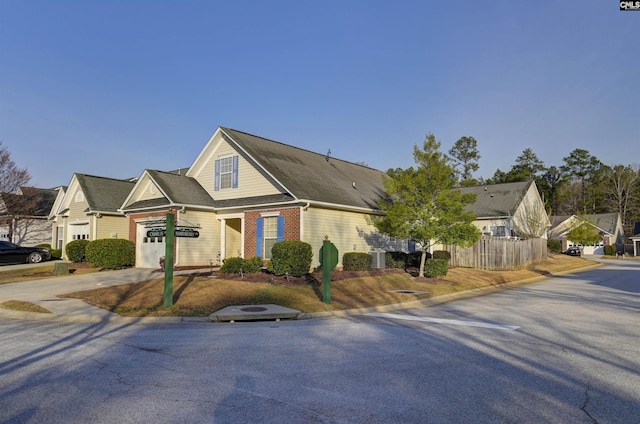 view of front facade featuring central air condition unit, concrete driveway, an attached garage, and fence