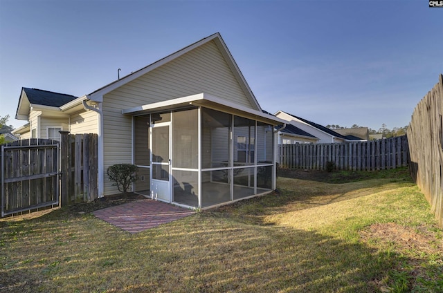 back of property with a lawn, a fenced backyard, and a sunroom