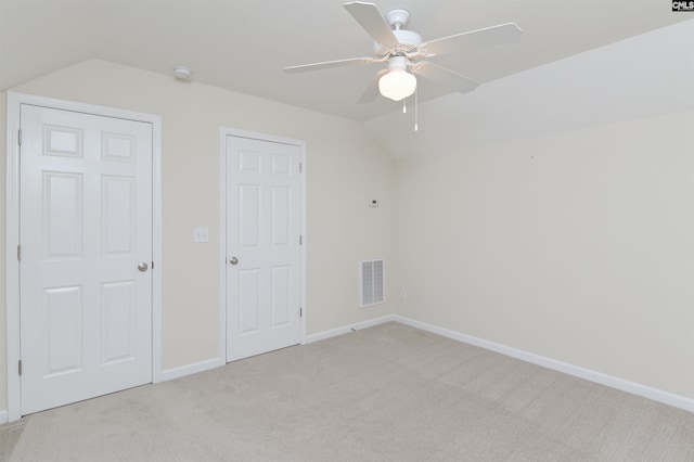 unfurnished bedroom with visible vents, baseboards, light colored carpet, ceiling fan, and vaulted ceiling