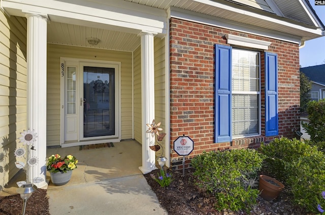 entrance to property with brick siding and a porch