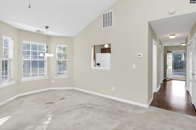 carpeted empty room with an inviting chandelier, baseboards, visible vents, and high vaulted ceiling