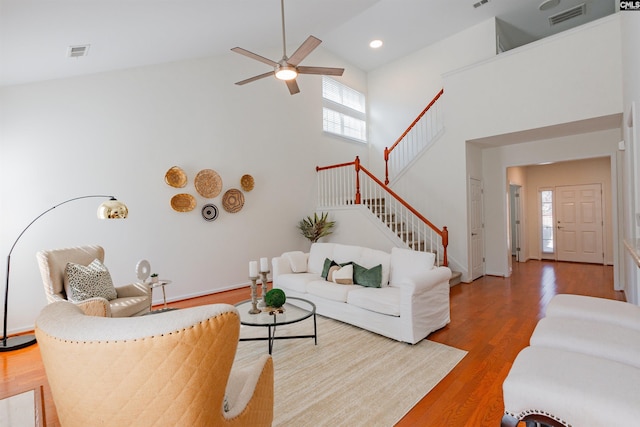 living area featuring ceiling fan, visible vents, wood finished floors, and stairs