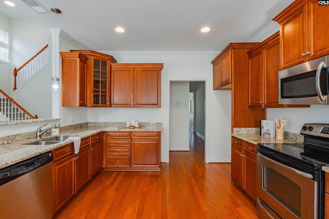 kitchen featuring light stone countertops, dark wood-style floors, a sink, appliances with stainless steel finishes, and crown molding