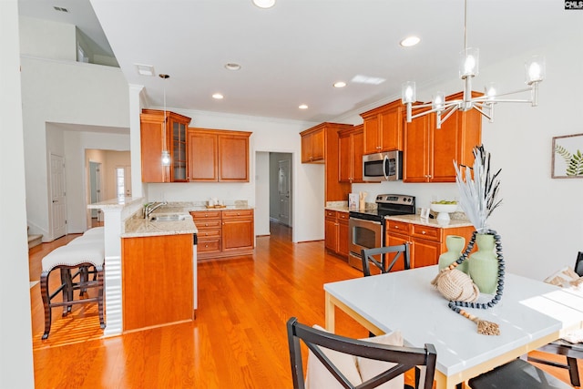 kitchen featuring brown cabinetry, appliances with stainless steel finishes, a peninsula, and a sink