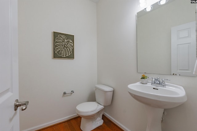 half bathroom featuring toilet, baseboards, and wood finished floors