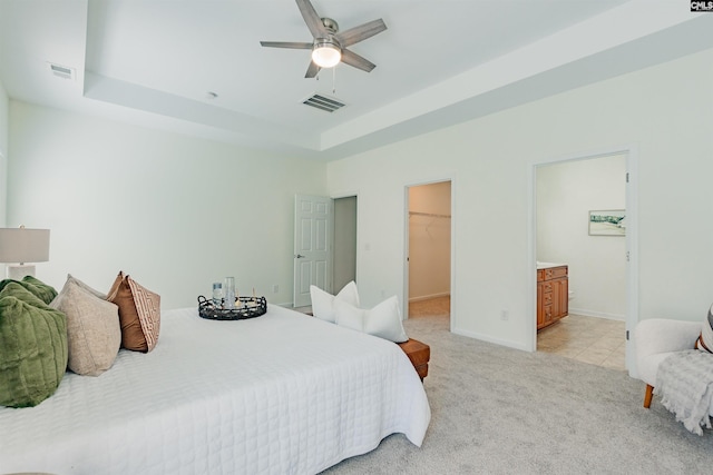 bedroom featuring light carpet, visible vents, a spacious closet, and a raised ceiling