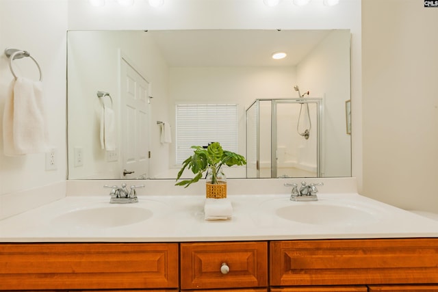 full bath with a shower stall, double vanity, and a sink