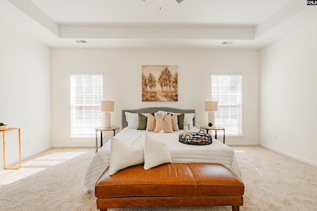 bedroom featuring visible vents, light carpet, and a raised ceiling