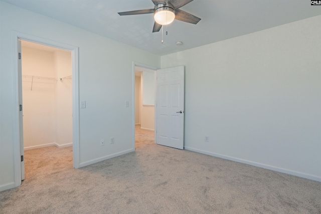 unfurnished bedroom with a walk in closet, baseboards, and carpet flooring