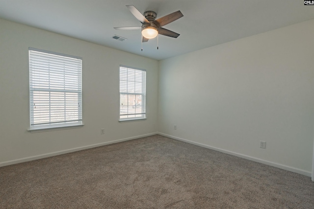 carpeted spare room featuring visible vents, baseboards, and a ceiling fan