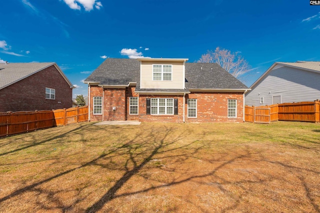 rear view of house featuring a patio, roof with shingles, a yard, a fenced backyard, and brick siding