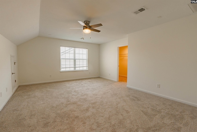 empty room with visible vents, lofted ceiling, a ceiling fan, baseboards, and light colored carpet