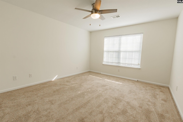 carpeted empty room with visible vents, baseboards, and a ceiling fan