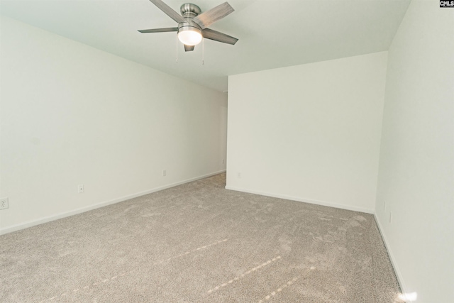 carpeted spare room featuring baseboards and a ceiling fan