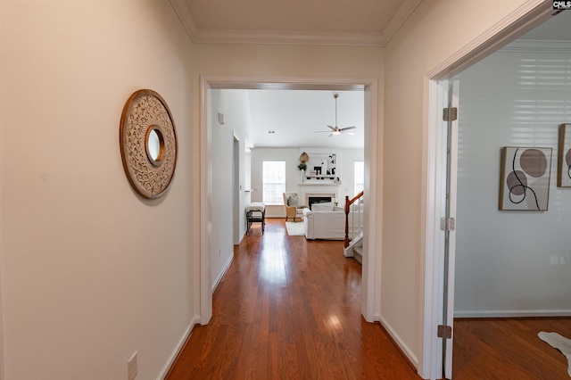 corridor featuring wood finished floors, baseboards, and ornamental molding