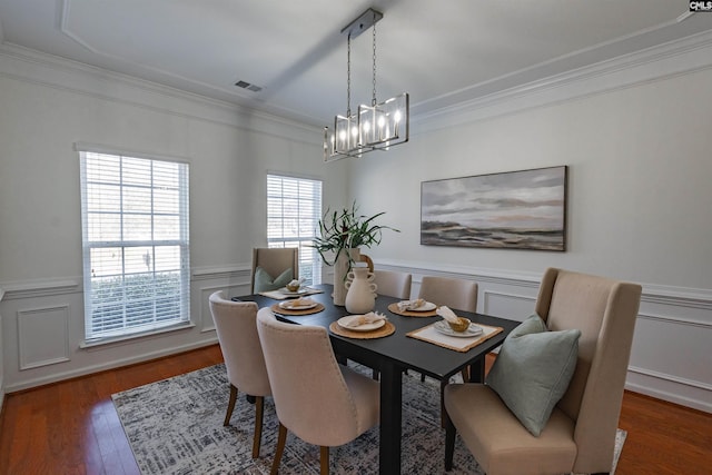 dining room with visible vents, ornamental molding, wood finished floors, an inviting chandelier, and wainscoting