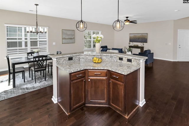 kitchen featuring dark wood-type flooring, ceiling fan with notable chandelier, open floor plan, and pendant lighting