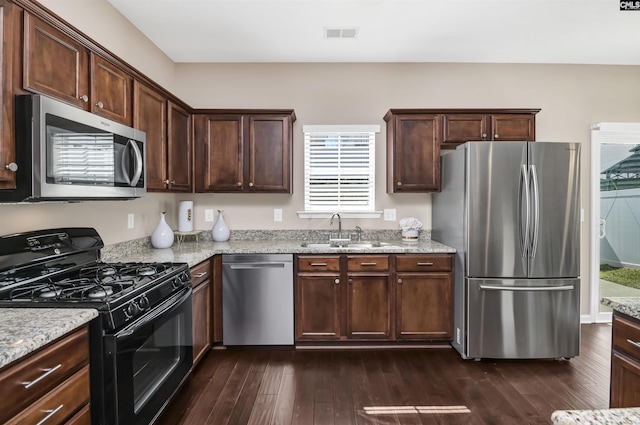 kitchen with visible vents, light stone counters, appliances with stainless steel finishes, dark wood-style floors, and a sink