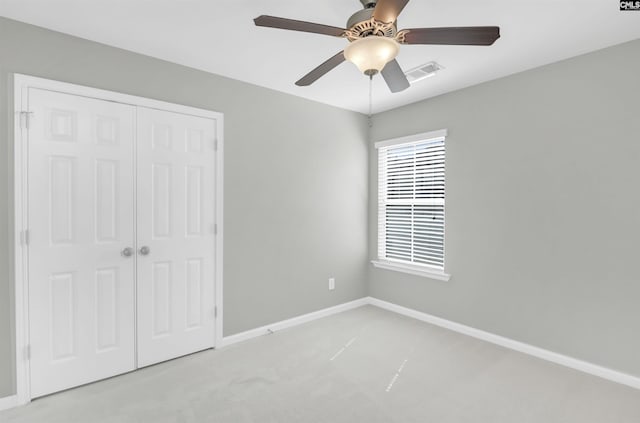 unfurnished bedroom with visible vents, a closet, baseboards, light colored carpet, and ceiling fan