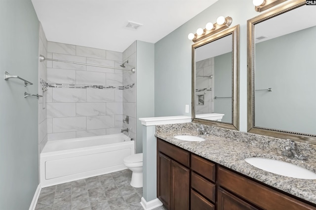 bathroom with double vanity, visible vents, toilet, and a sink