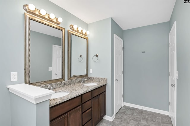 full bath with a sink, baseboards, and double vanity