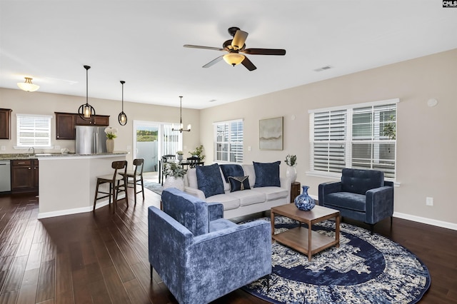 living area featuring visible vents, baseboards, dark wood-style floors, and ceiling fan with notable chandelier