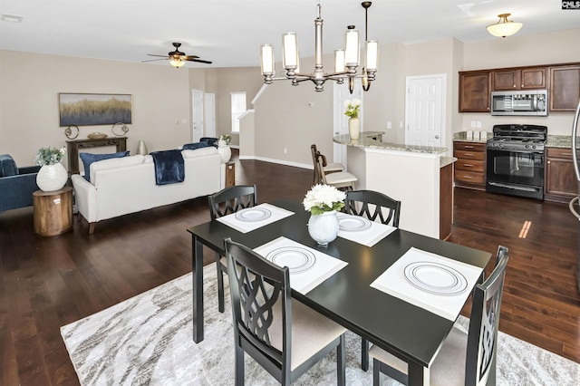 dining space featuring dark wood finished floors, ceiling fan with notable chandelier, and baseboards