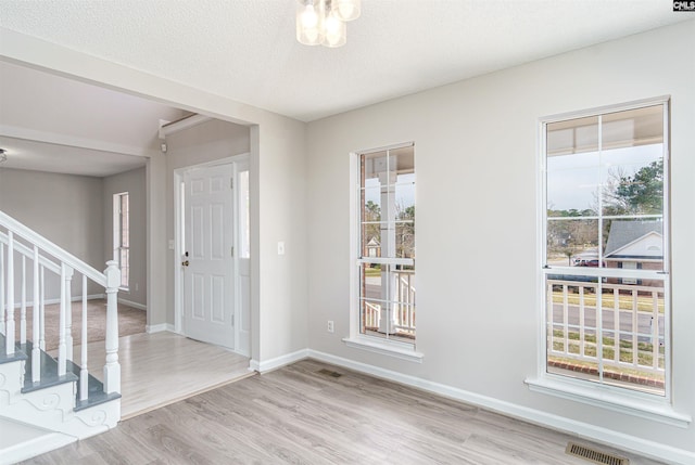 entryway featuring visible vents, baseboards, stairs, wood finished floors, and a textured ceiling