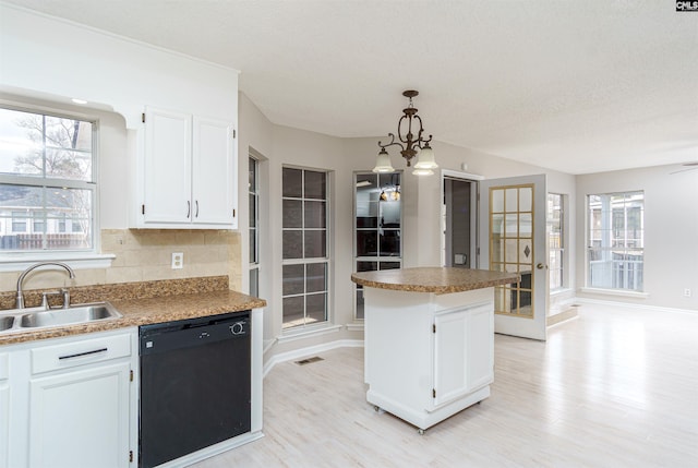 kitchen featuring backsplash, a healthy amount of sunlight, dishwasher, white cabinets, and a sink