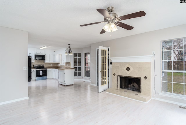 unfurnished living room featuring baseboards, a healthy amount of sunlight, light wood-style flooring, and a ceiling fan