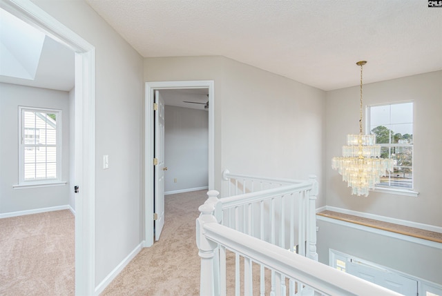 hallway with an inviting chandelier, carpet flooring, an upstairs landing, and baseboards