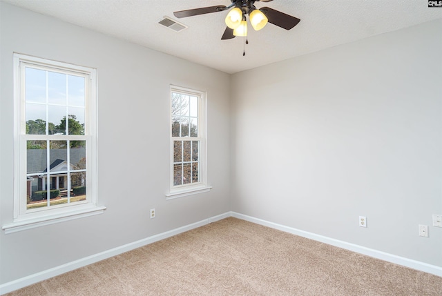 unfurnished room featuring visible vents, a textured ceiling, carpet, baseboards, and ceiling fan