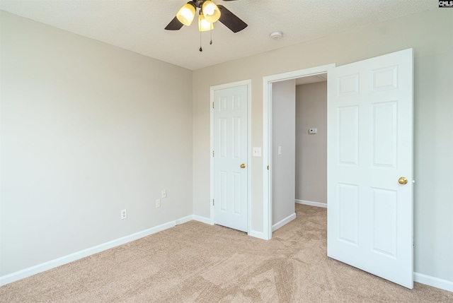 unfurnished bedroom featuring light carpet, a textured ceiling, baseboards, and a ceiling fan