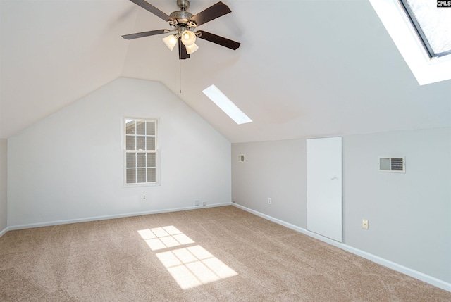 additional living space featuring visible vents, baseboards, carpet, ceiling fan, and vaulted ceiling with skylight