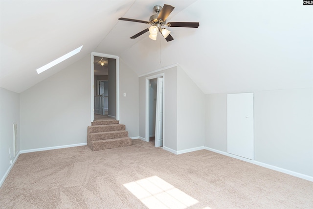 bonus room with carpet flooring, vaulted ceiling with skylight, baseboards, and a ceiling fan