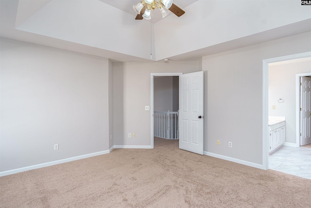 unfurnished bedroom with a spacious closet, light colored carpet, connected bathroom, and baseboards