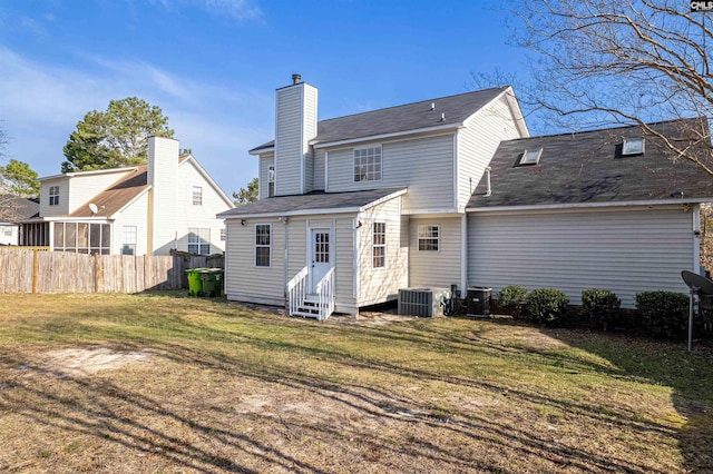 back of house with fence, entry steps, a lawn, cooling unit, and a chimney