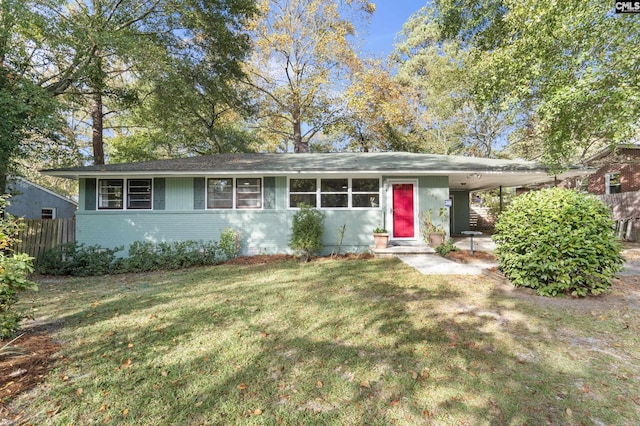 ranch-style house featuring a front yard, fence, brick siding, and a carport