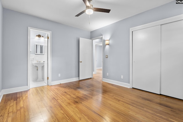 unfurnished bedroom featuring a closet, ensuite bathroom, light wood-type flooring, and baseboards