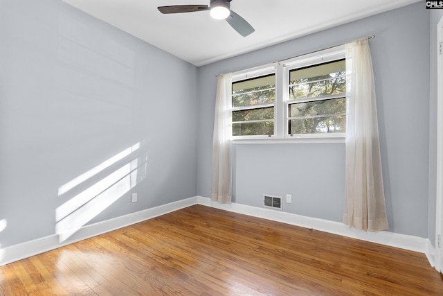 spare room featuring visible vents, baseboards, wood finished floors, and a ceiling fan