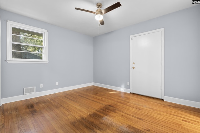 empty room featuring visible vents, baseboards, hardwood / wood-style floors, and a ceiling fan